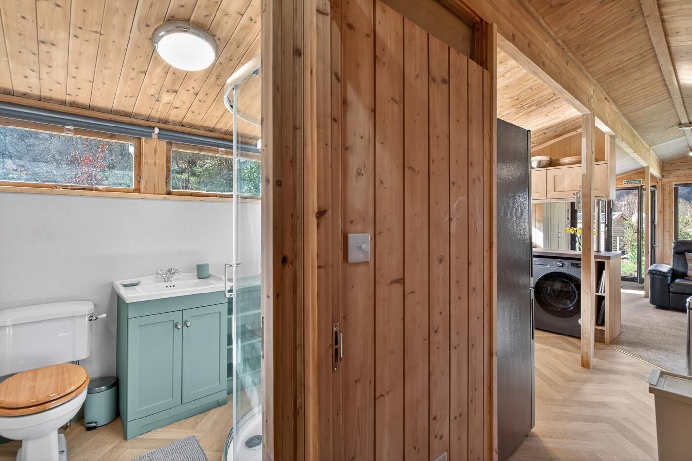 Een houten interieur met een badkamer, een wasmachine en een zithoek.