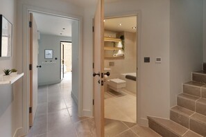 A modern interior with a hallway leading to a bathroom, featuring a staircase, a toilet, and a sink. - 2 Bed in Whitstable (oc-s39502) (Whitstable)