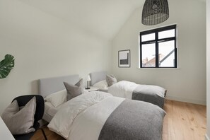 A bedroom with two beds, a bedside table, a lamp, a hanging light fixture, a window, and a plant. - 2 Bed in Whitstable (oc-s39502) (Whitstable)