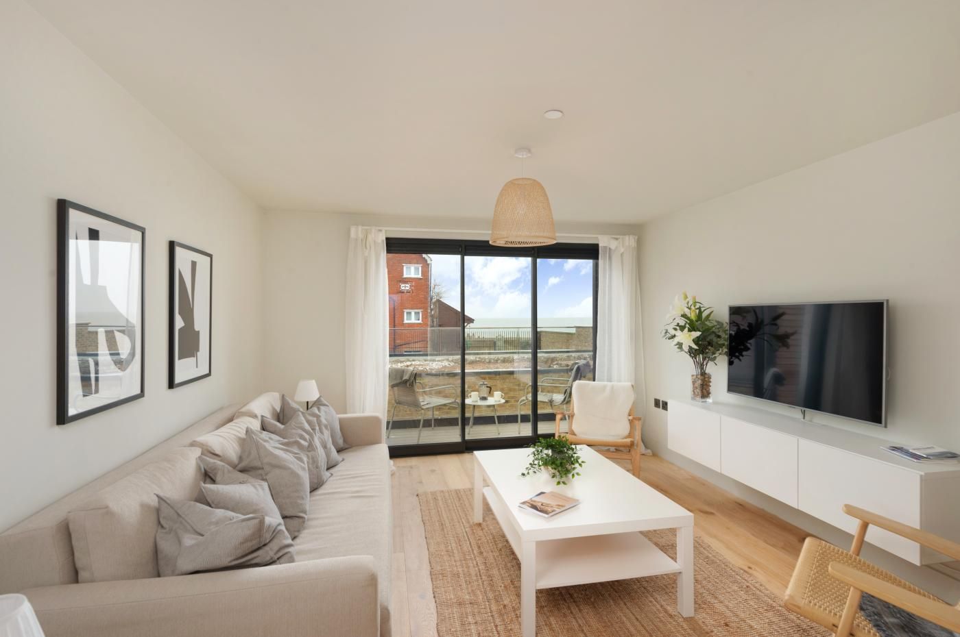 A modern living room with a sofa, a coffee table, a TV, and a balcony with a view.
