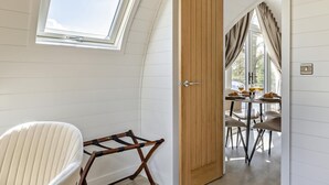 Una habitación con tragaluz, una puerta que da a un comedor y una silla.