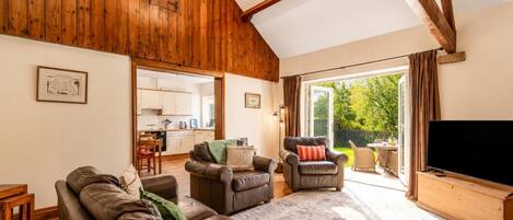 A spacious living area with a wooden ceiling, a television, and a view of the outdoors.