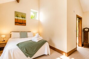 A bedroom with a bed, pillows, a green throw blanket, a bedside lamp, a painting, a window, and a wooden door. - 2 Bed in Gransmoor (oc-w37884) (Gransmoor)