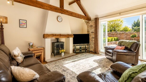 A living room with a fireplace, leather sofas, a television, and a large window. - 1 Bed in Gransmoor (oc-s37885) (Gransmoor)