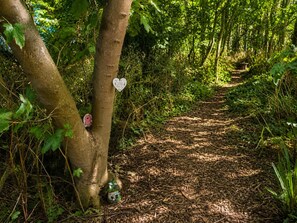 A forest path with a heart-shaped sign on a tree and a small house decoration at the base. - 1 Bed in Gransmoor (oc-s37885) (Gransmoor)