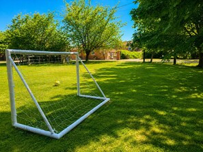 A soccer goal on a well-maintained grassy field with trees and a building in the background. - 1 Bed in Gransmoor (oc-s37885) (Gransmoor)