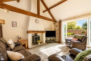 A living room with a fireplace, leather sofas, a television, and a large window. - 2 Bed in Gransmoor (oc-c37883) (Gransmoor)