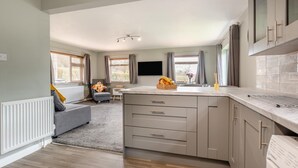 A compact kitchen with a built-in oven, a dining area with a table and chairs, and a seating area with a sofa. - 3 Bed in Matlock Moor (oc-m36349) (Matlock)