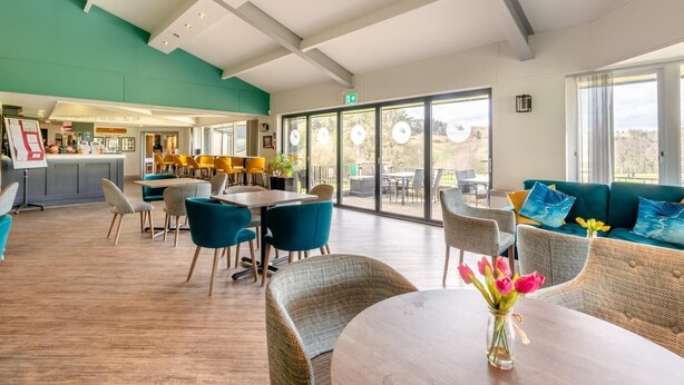 A spacious indoor area with a bar, seating arrangements, and large windows offering a view. - 3 Bed in Matlock Moor (oc-m36349) (Matlock)