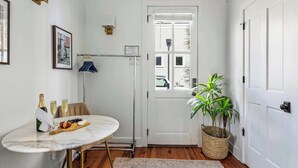 En lys og moderne gang med en hvid dør, et lille vindue og en potteplante.
