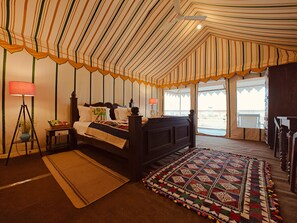 Habitación tipo tienda de campaña con cama, lámpara, alfombra y vistas al exterior.