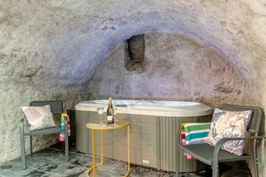 A hot tub with two chairs, a small table, and a bottle of champagne. - 2 Bed in Tenby (oc-b41399) (Tenby)