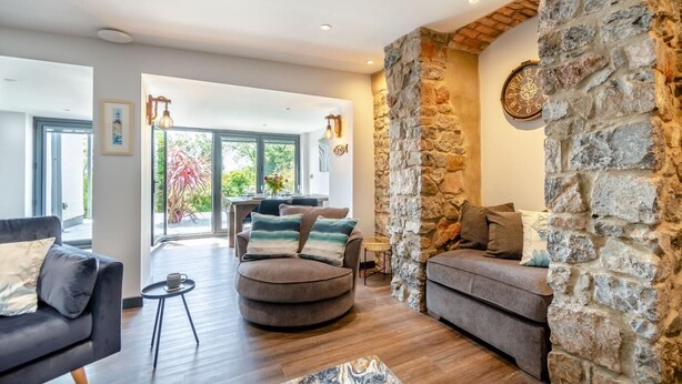 Ein modernes Wohnzimmer mit einer Wand aus Stein, einem runden Couchtisch und einer Couch mit Kissen.