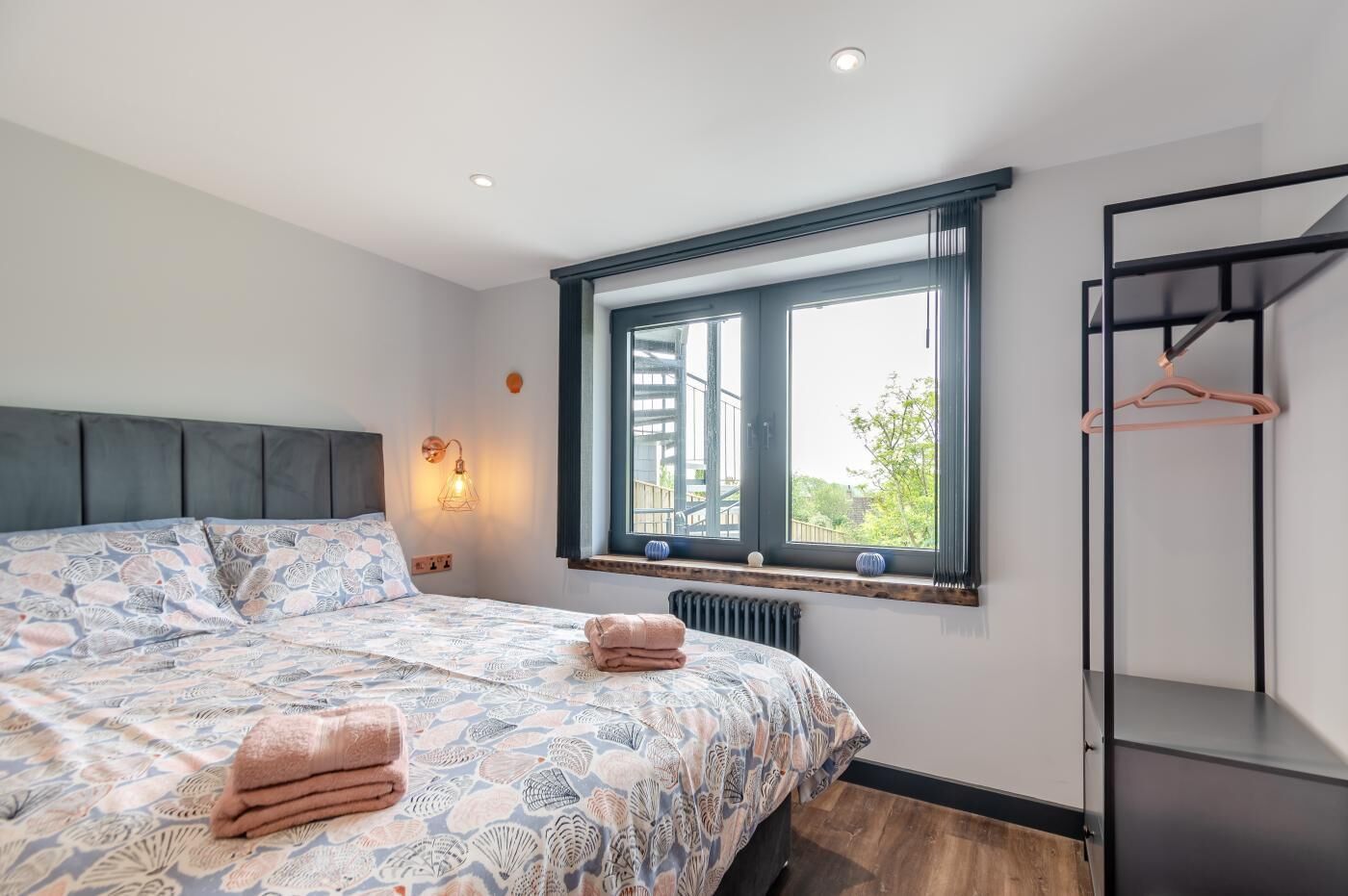 A bedroom with a bed, a window, a radiator, and a wardrobe.