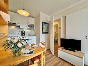 A compact living space with a kitchen, dining area, and a TV. - Ferienwohnung im Seepark Sellin mit Balkon (Sellin)