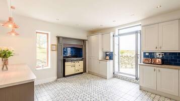 A modern kitchen with a built-in stove, white cabinets, and patterned floor tiles.