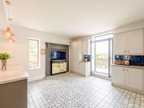 Une cuisine moderne dotée d’une cuisinière intégrée, de meubles blancs et de carreaux de sol à motifs.