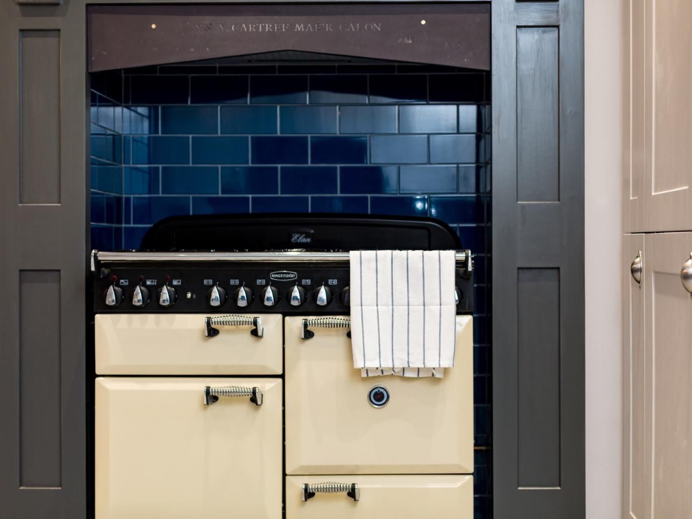 A kitchen with a stove, oven, and a blue-tiled backsplash.