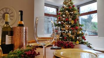 A dining table with a wine bottle, a glass, a plate, and a Christmas tree.