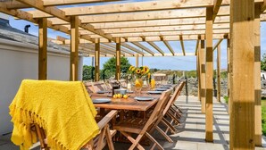 An outdoor wooden pergola with a dining table set for six, surrounded by chairs. - 7 Bed in Holyhead (oc-55866) (Bae Trearddur)