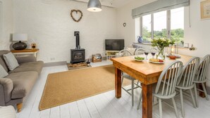 A cozy living room with a sofa, TV, fireplace, dining table, and chairs. - 2 Bed in Warkworth (oc-coq139) (Warkworth)