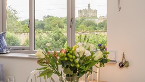 A room with a large window, a vase with flowers, a blue patterned pitcher, and a wall-mounted light fixture. - 2 Bed in Warkworth (oc-coq139) (Warkworth)