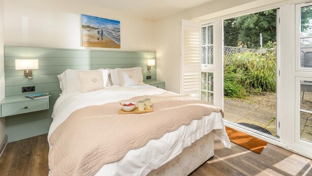 A bedroom with a bed, bedside tables, a painting, and a view through a glass door. - 2 Bed in Warkworth (oc-coq139) (Warkworth)