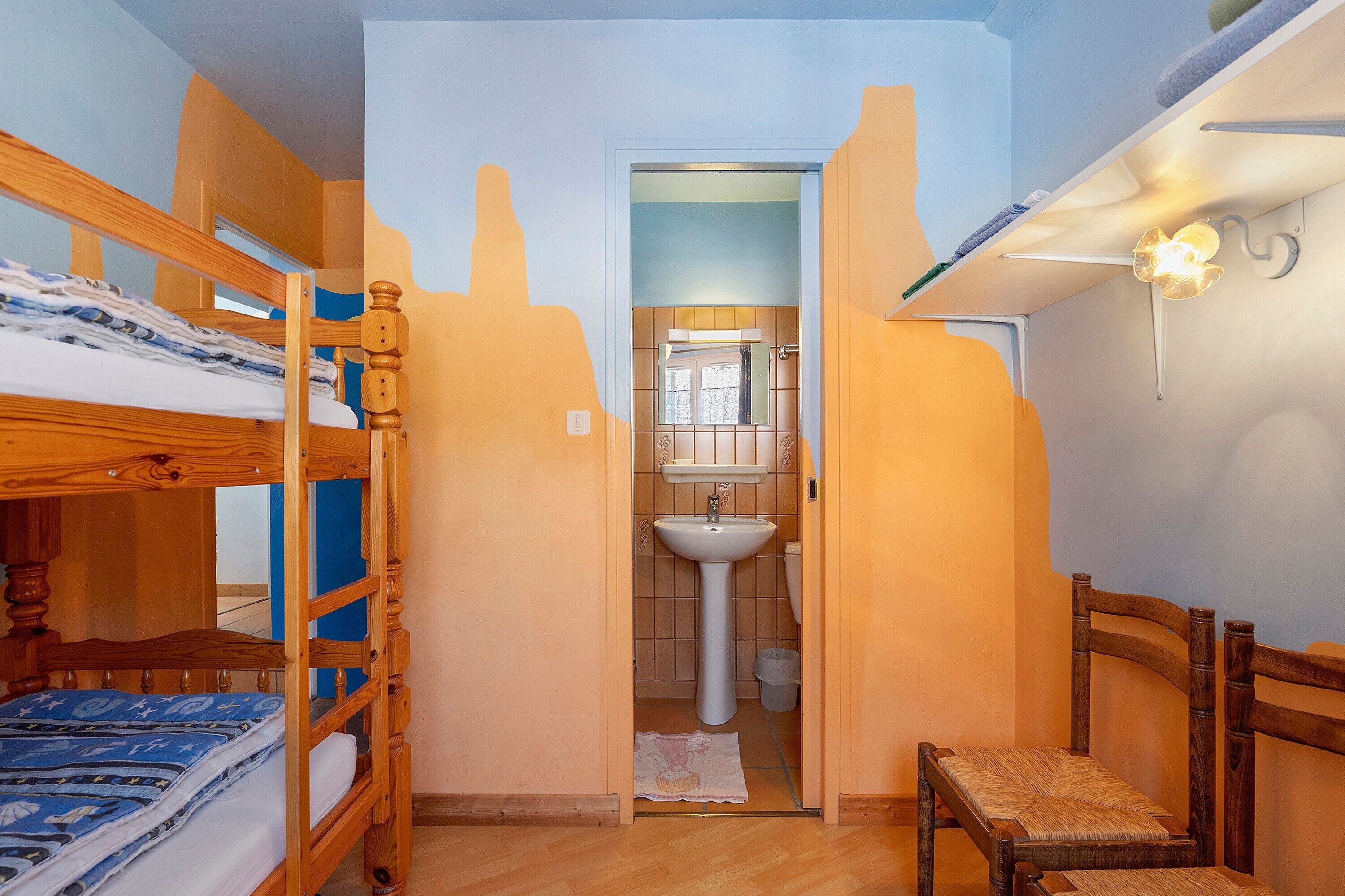 Una habitación con literas, un lavamanos y una silla.