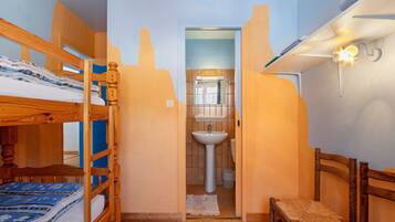 Una habitación con literas, un lavamanos y una silla.