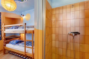 A bunk bed with a wooden frame and a shower with a handheld showerhead.
