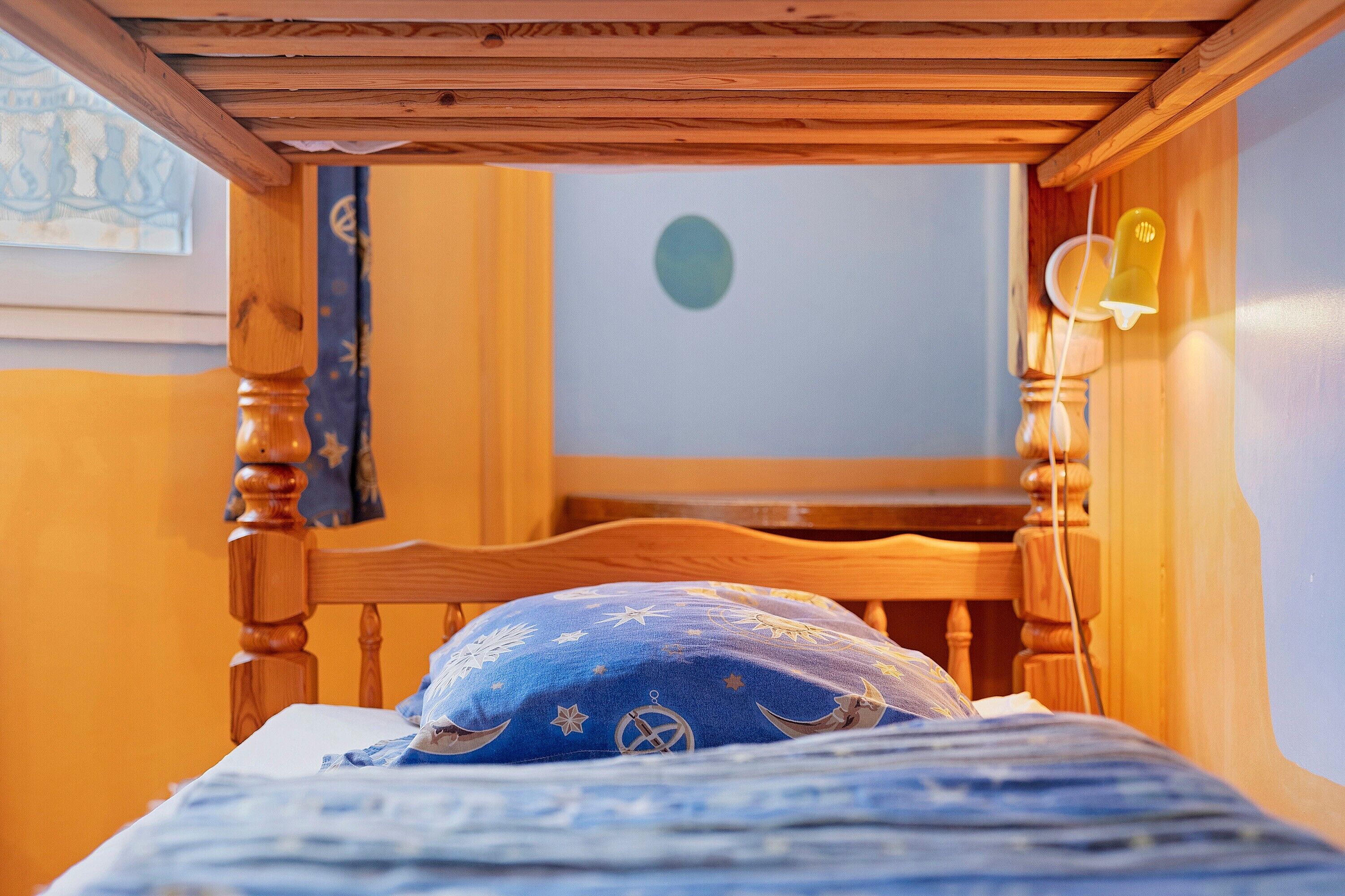 Een houten bed met een blauw kussen en een muur met een ronde decoratie.