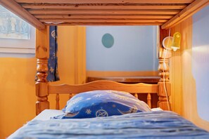 Een houten bed met een blauw kussen en een muur met een ronde decoratie.