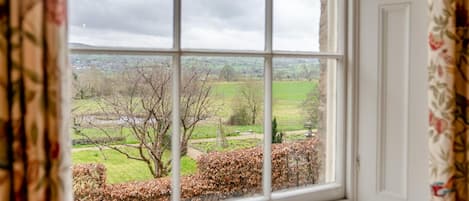 A window with a view of a rural landscape, including fields and trees.