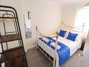 A bedroom with a bed, a wooden shelf, a mirror, and a door. - 271 Wragby Road (Lincoln)