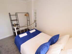 A bed with a blue quilt, two pillows, and a white blanket. - 271 Wragby Road (Lincoln)