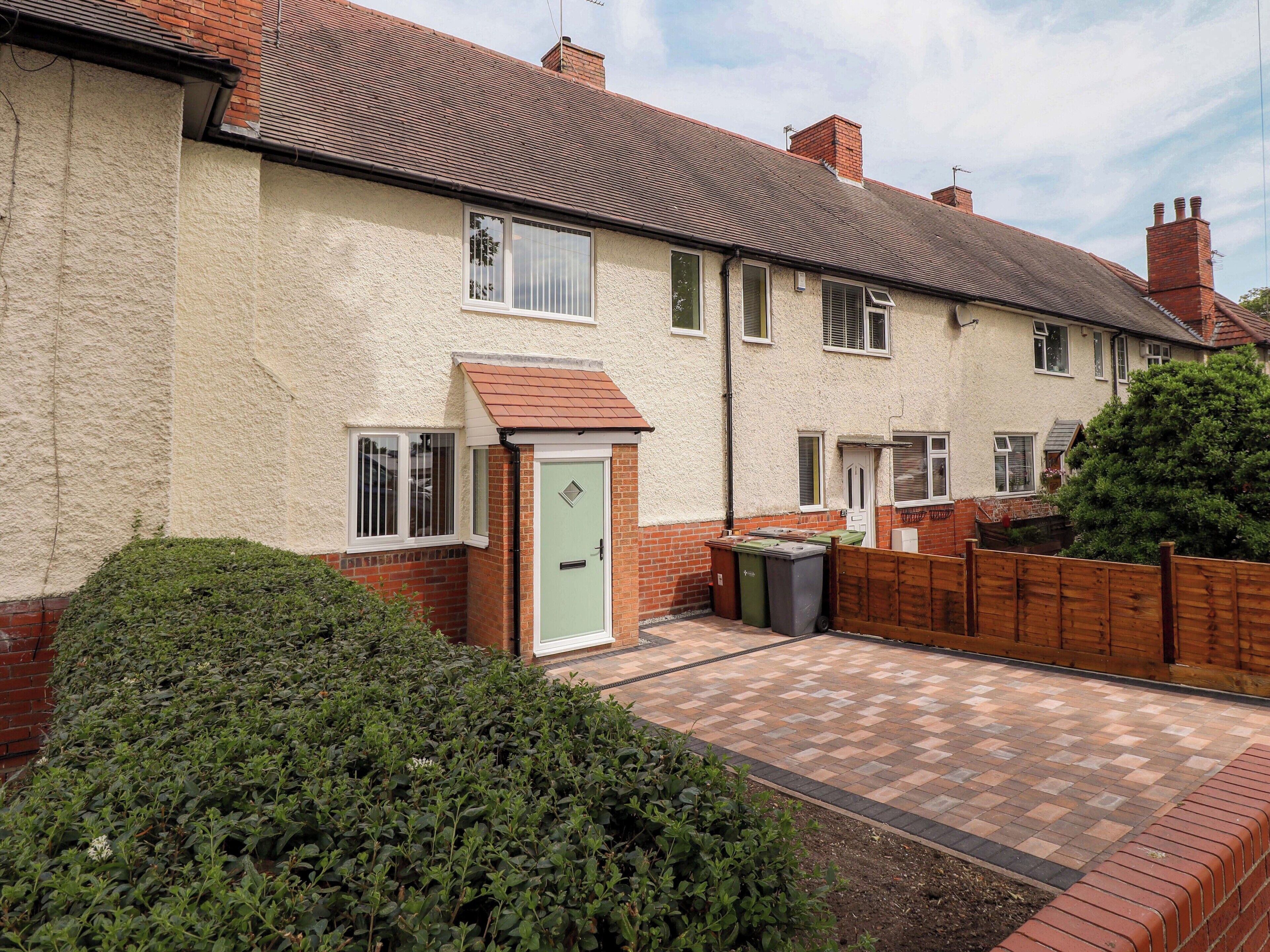 A residential house with a paved driveway, a front door, and a small garden area.