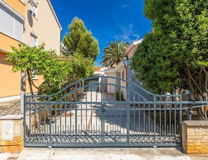 A gated entrance with a metal gate, a stone wall, and a building with a tiled roof. - Pet-friendly Apartment With Terrace (Medulin)