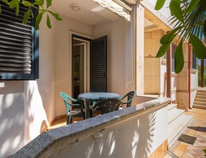 A balcony with a table and chairs, a door, and a window with shutters. - Pet-friendly Apartment With Terrace (Medulin)