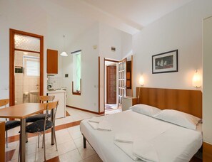 A hotel room with a bed, a desk, a chair, a kitchenette, and a bathroom. - Pet-friendly Apartment With Terrace (Medulin)