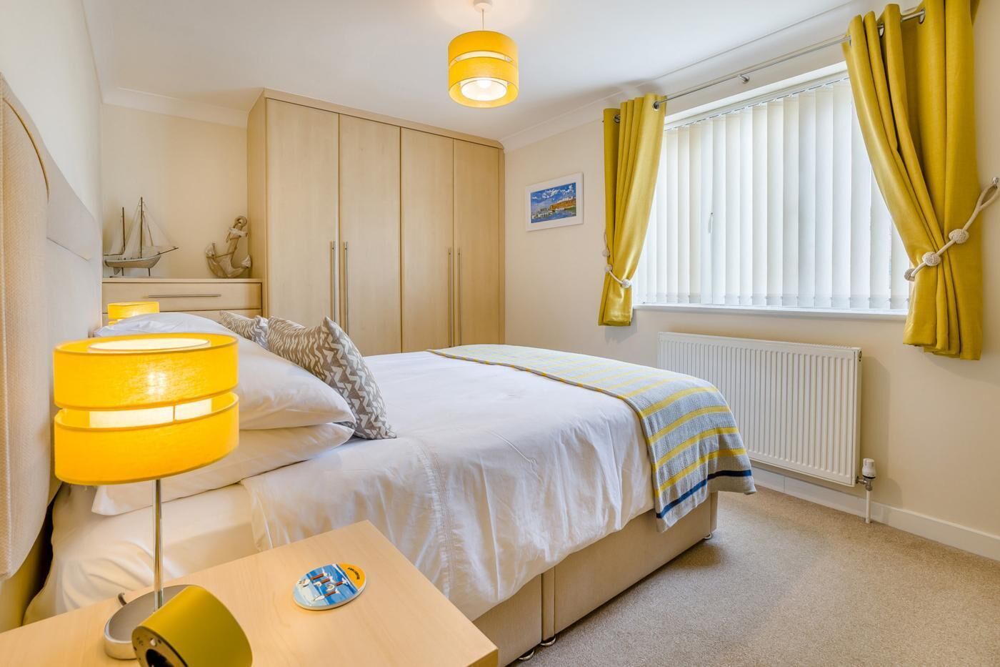 A bedroom with a bed, bedside table, lamp, and a window with curtains.