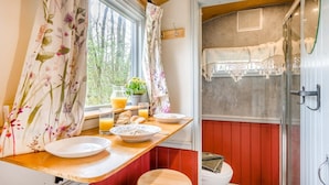Ett litet badrum med dusch, toalett och ett fönster med gardiner.
