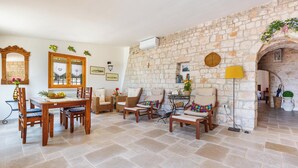 Una habitación con paredes de piedra, una mesa de comedor, sillas, un sofá y una lámpara.