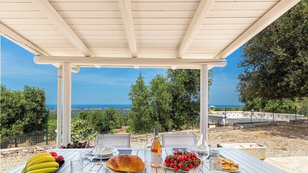 Un área de comedor al aire libre con una mesa dispuesta para dos, con vistas a un paisaje pintoresco.