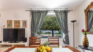 Un comedor con una mesa dispuesta para dos, un televisor y un frutero.