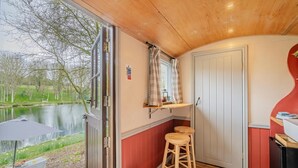 A room with a view of a lake, a wooden ceiling, a door, a stool, and a small table with items on it. - 1 Bed in Edgefield (oc-c39014) (Edgefield)