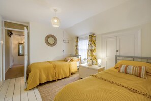 A room with two beds, a bedside table, a mirror, a hanging light fixture, and a door leading to another room. - 2 Bed in Overstrand (oc-c41369) (Overstrand)