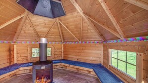 Een houten hut met een open haard, banken en ramen.