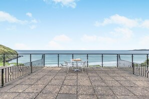 A terrace with a table and chairs overlooking the sea. - 2 Bed in Putsborough (oc-s40237) (Croyde)