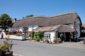 A traditional building with a thatched roof, white walls, and a small porch area with potted plants. - 2 Bed in Putsborough (oc-s40237) (Croyde)