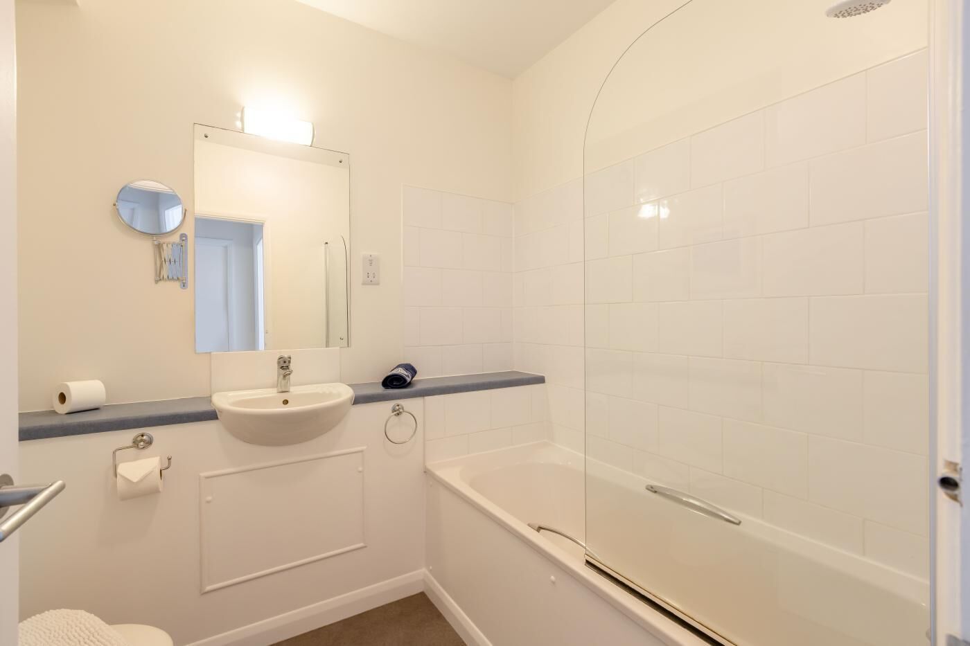 Un baño con lavamanos, espejo, inodoro y zona de ducha.